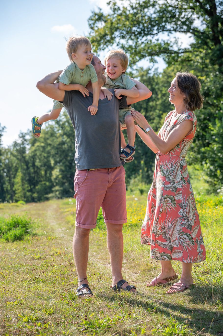 Familie mit zwei kleinen Kindern in der Natur, fröhlich miteinander spielend.